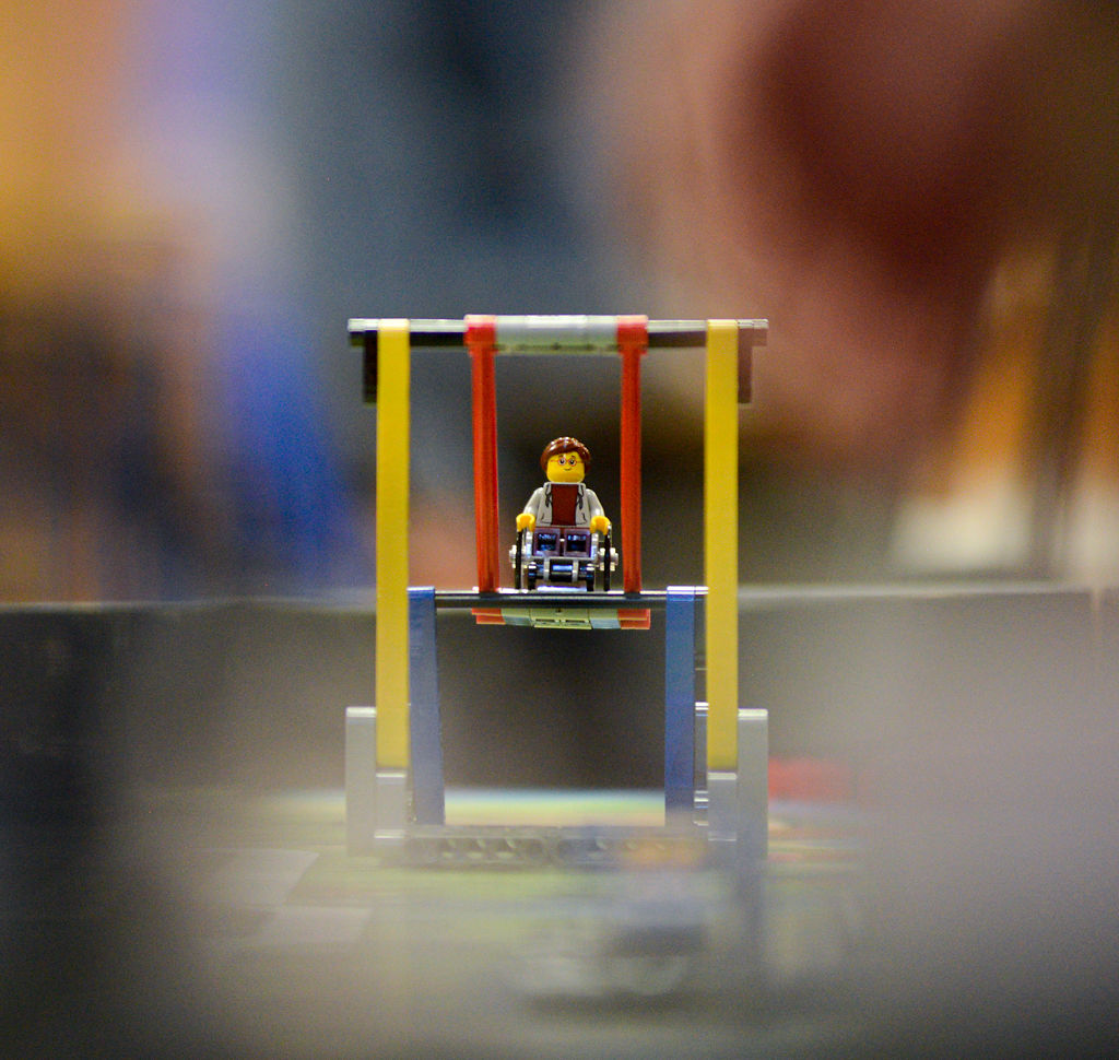 A LEGO figurine sits on a LEGO swing as part of the mission course